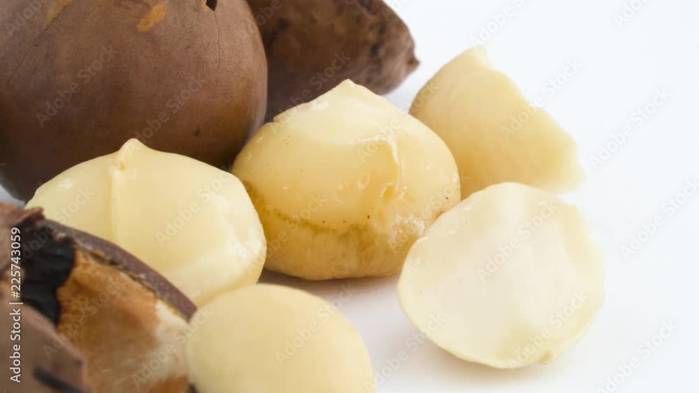 Macro shooting of macadamia nut inshelled, blanched whole and half macadamia nuts as well as their shells. Slowly rotating on the turntable isolated on the white background. Close up. Macro. Macro shooting of macadamia nut inshelled, blanched whole and half macadamia nuts as well as their shells. Slowly rotating on the turntable isolated on the white background. Close up. Macro.