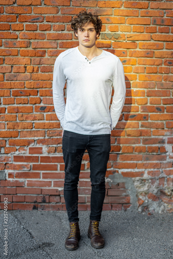Distant plan of young attractive man standing on red brick background. Distant plan of young attractive man standing on red brick background.