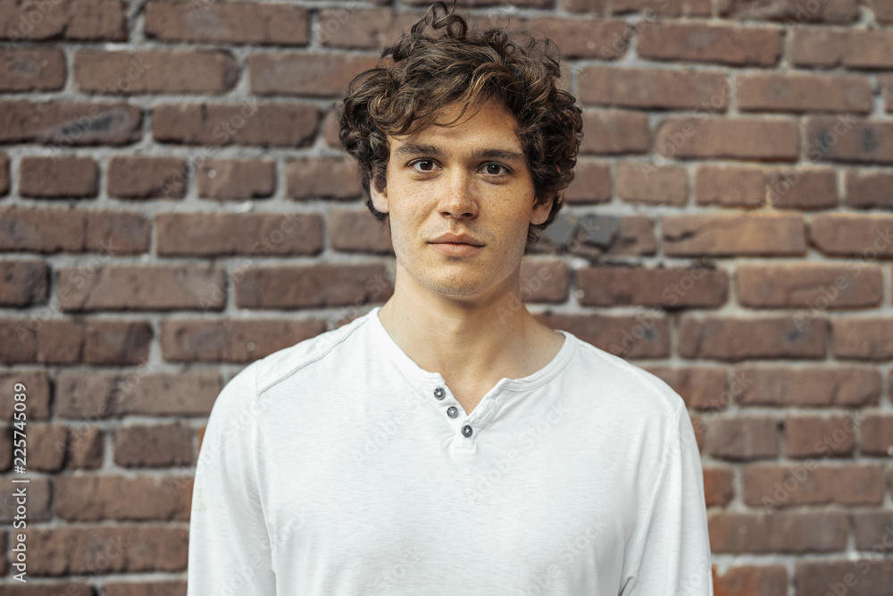 Close up of young attractive man standing on red brick background. Close up of young attractive man standing on red brick background.