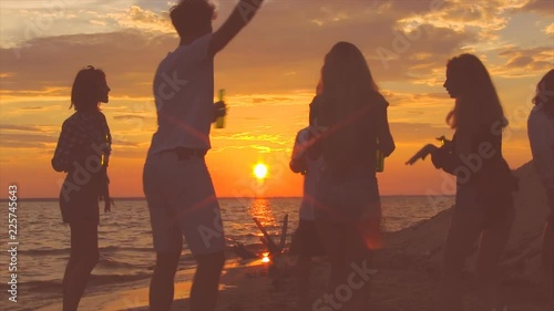 Group of people dancing at the beach near the bonfire.