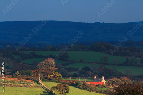 Scenic view of the Dartmoor hills. Low autumn sun illuminates a lonely house. Devon UK