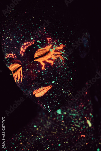 Portrait of a girl painted in fluorescent powder. Halloween concept.