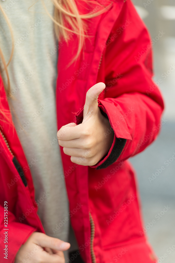 Hand of baby shows thumbs up gesture. Kid wear warm jacket show gesture of approvement or accept. She likes this. Thumb up gesture meaning like and agreement. Thumbs up and like concept Hand of baby shows thumbs up gesture. Kid wear warm jacket show gesture of approvement or accept. She likes this. Thumb up gesture meaning like and agreement. Thumbs up and like concept