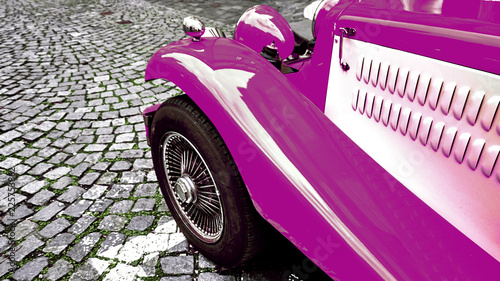 Front side part of vintage classic purple hot rod car on a cobble road