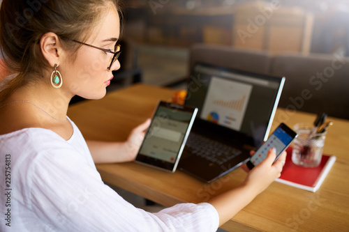 Tablou pe pânză Mixed race woman in glasses working with multiple electronic internet devices