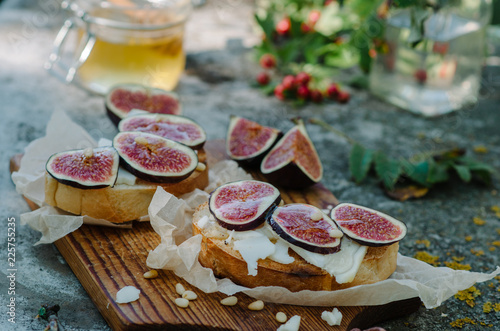 Bruschetta with cheese, fresh figs, pine nuts and honey on rustic board