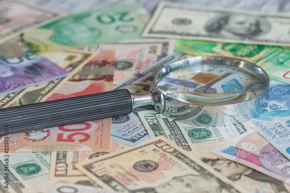 Different currency and magnifying glass, soft focus background Different currency and magnifying glass, soft focus background