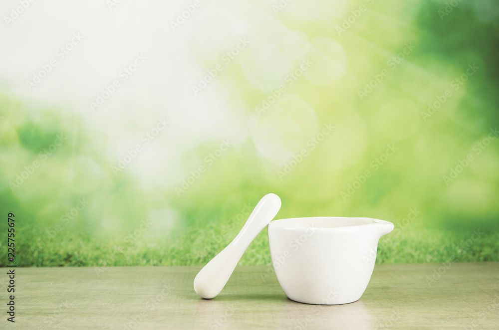 Kitchen tool white ceramic mortar and pestile on wooden table, green fresh bokeh background. Minimal product catalog background concept.