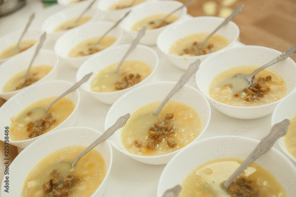 Lunch set (vegetable soup, crackers, plates, spoon) were prepared for children on the long table in the kindergarten Lunch set (vegetable soup, crackers, plates, spoon) were prepared for children on the long table in the kindergarten