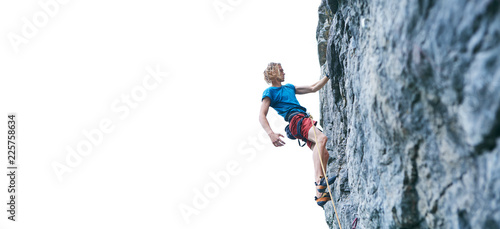 male rock climber resting while climbing the challenging route on the rocky wall