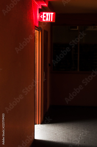 red exit sign board with light coming out of the door