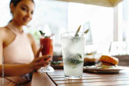 Close up of young attractive woman holding glass with smoothie at street cafe.