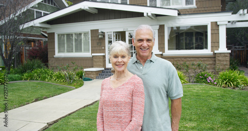 Valokuva Senior couple standing smiling in front of new home