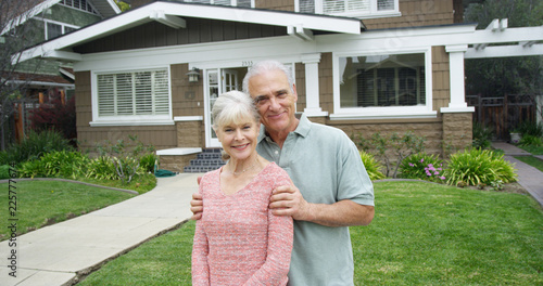 Senior couple standing smiling in front of new home