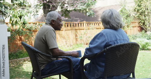 Mature African couple sitting in backyard drinking coffee