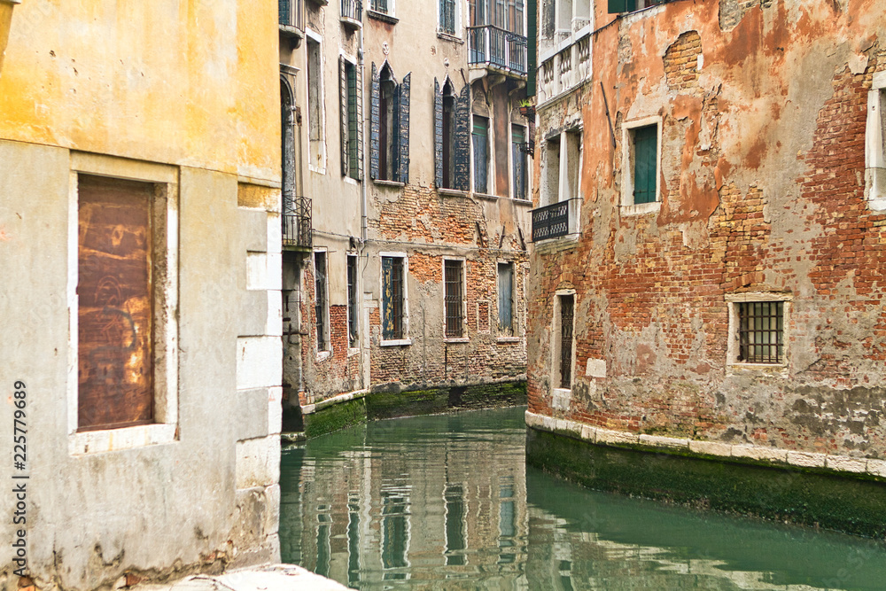 A narrow canal runs between two buildings in Venice, Italy A narrow canal runs between two buildings in Venice, Italy