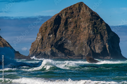 Haystack Rock (Chief Kiawanda) watches waves rolling into the shore in Pacific City Oregon.