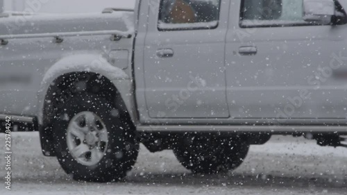 Slow motion, close up, DOF large pickup truck drives along the slippery snowy road while a blizzard makes the road conditions even worse photo