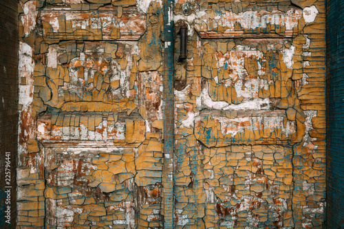 Old wooden door with handle and lock. Many layers of paint in different colors.