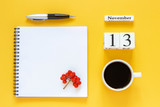 Autumn composition. Wooden calendar November 13 cup of coffee, empty open notepad with pen and yellow oak leaf on yellow background. Top view Flat lay Mockup Concept Hello November