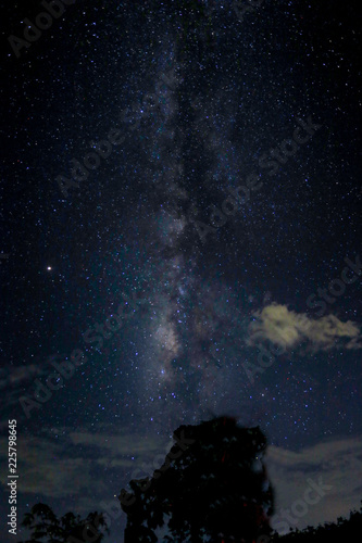 Starry sky and Milky Way arch with cloud in the blue sky.