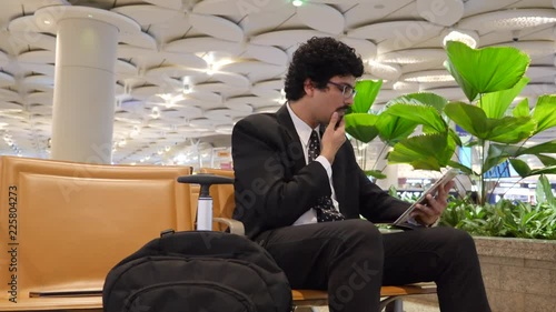 Office going young man using mobile phone, tablet while travelling.