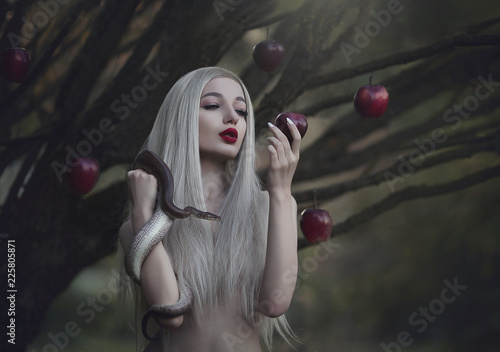 Eve with the serpent the tempter and the apple of sin. Young beautiful nude girl with very long white hair with a snake under the apple tree.