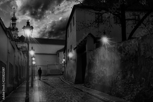 Photography Mysterious narrow street of Prague at sunset with the silhouette of a man walkin
