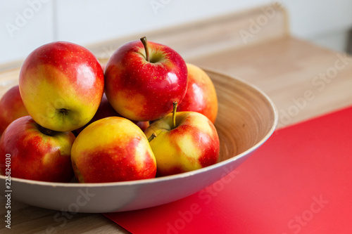 rot gelbe äpfel in einer obstschale und mit einem roten schneidebrett