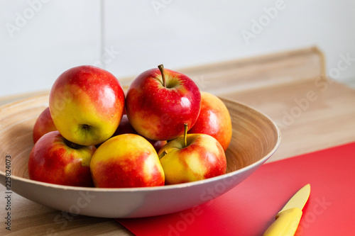 rot gelbe äpfel in einer obstschale,mit einem roten schneidebrett und einem gelben messer