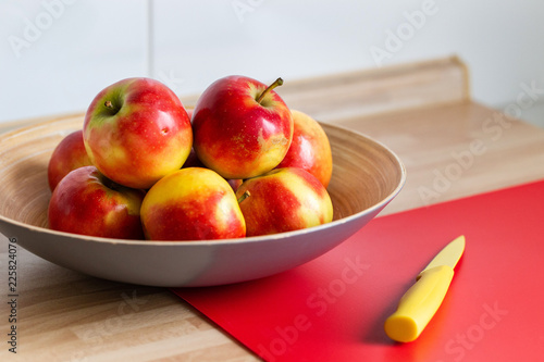 rot gelbe äpfel in einer obstschale,mit einem roten schneidebrett und einem gelben messer 