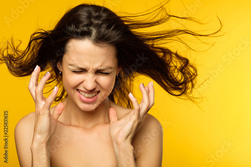 stress and emotional breakdown. feelings expression. angry woman in distress. young beautiful brown haired girl portrait on yellow background.