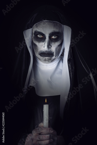 Canvas Print frightening evil nun with a lit candle