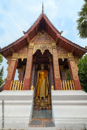 Big golden statue of standing Buddha at the Vat Sensoukharam (Sene Souk Haram) Temple in Luang Prabang, Laos, viewed from the front. photo