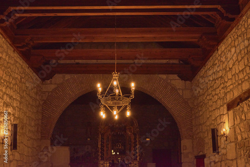 View from inside the stone church with lit antique lamps and the image of the virgin background in Las Ventas with Peña Aguilera, Toledo, Spain photo