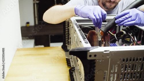 Crane shot. Repairing of computer. Male hands cleaning computer cooler from dust with a vacuum cleaner