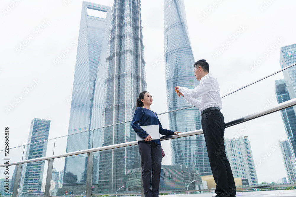 Young businesswoman and man talking in city financial district, Shanghai, China Young businesswoman and man talking in city financial district, Shanghai, China