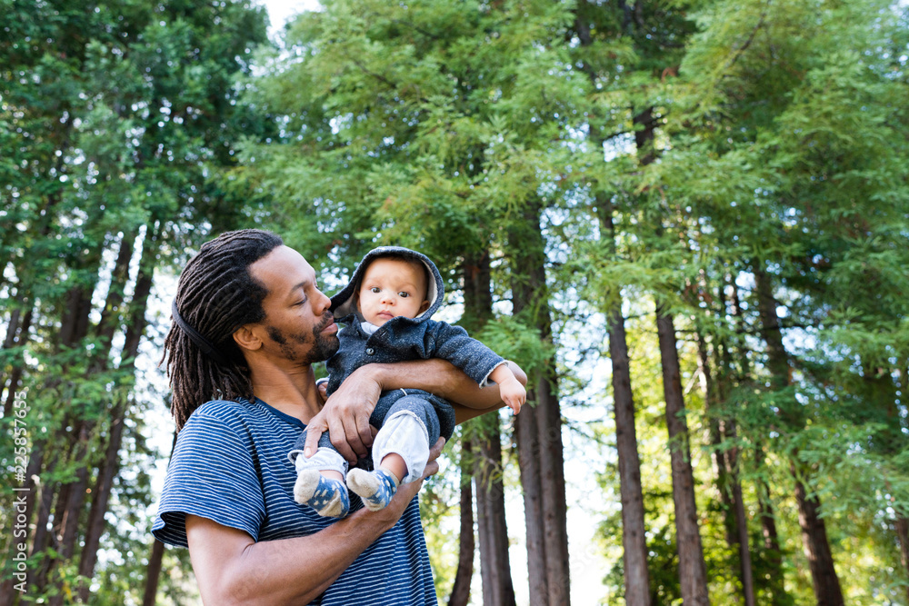 Mature man in forest carrying baby son in arms Mature man in forest carrying baby son in arms