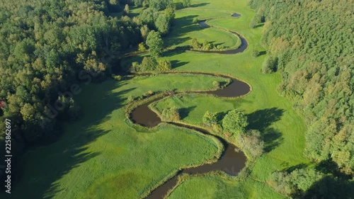 Aerial view of beautiful curvy river flowing between forest and green grassland photo