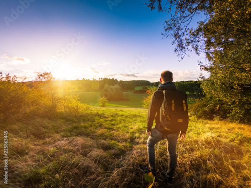 Wanderer genießt Aussicht über bunte Herbstlandschaft bei Sonnenlicht