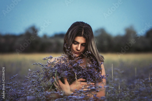 Foto The girl in the field, hiding behind the steppe violet branchy flowers limonium