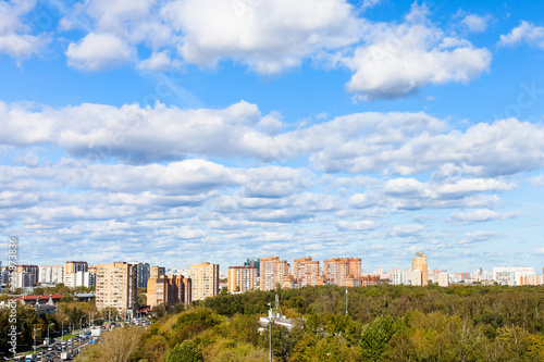 white clouds in blue sky over street and park photo