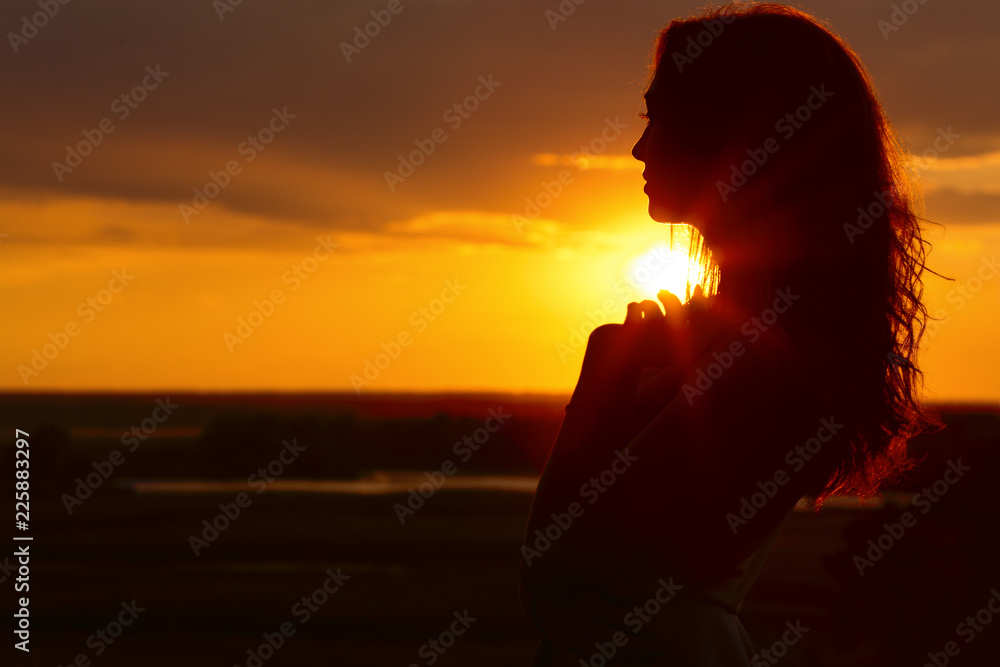 silhouette of a beautiful girl at sunset in a field, face profile of young  woman on nature Stock Photo