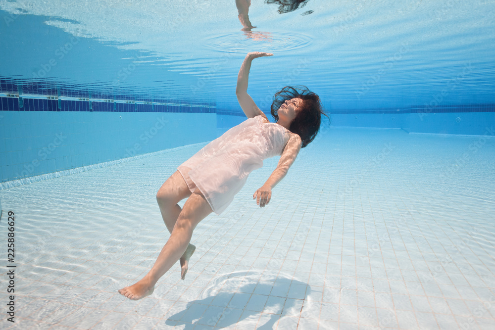 Young attractive girl swim underwater in swimming pool in pink dress. Diving  and floating under water surface. Playing with reflections and waves. Touch  water mirror with her hand Stock Photo | Adobe