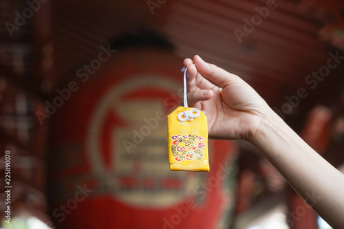 Japanese lucky charm. A hand holding a yellow omamori or A Japanese lucky charm to grant a wish fulfillment