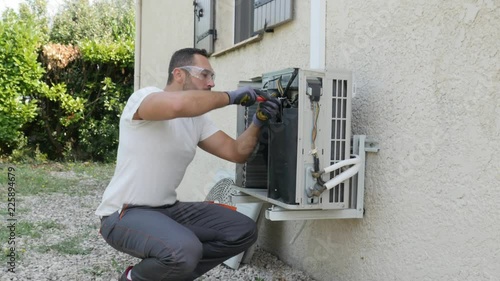 handsome young man electrician installing air conditioning in a client house
