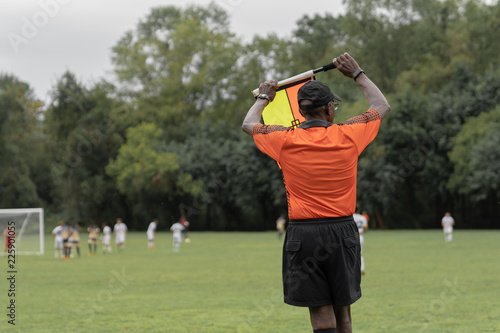 African American Soccer Referee with Orange Top Holding Substitution Flag Symbol