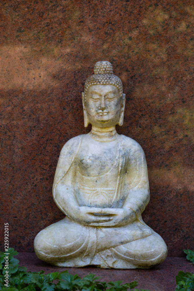 Sitzender Buddha vor einer roten Marmorplatte Sitzender Buddha vor einer roten Marmorplatte