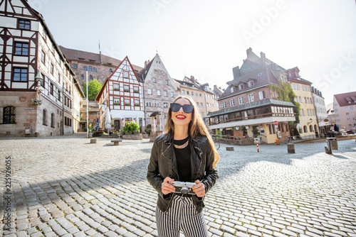 Portrait of a young woman tourist standing on the beautiful city square with old buildings, traveling in Nurnberg, Germany photo