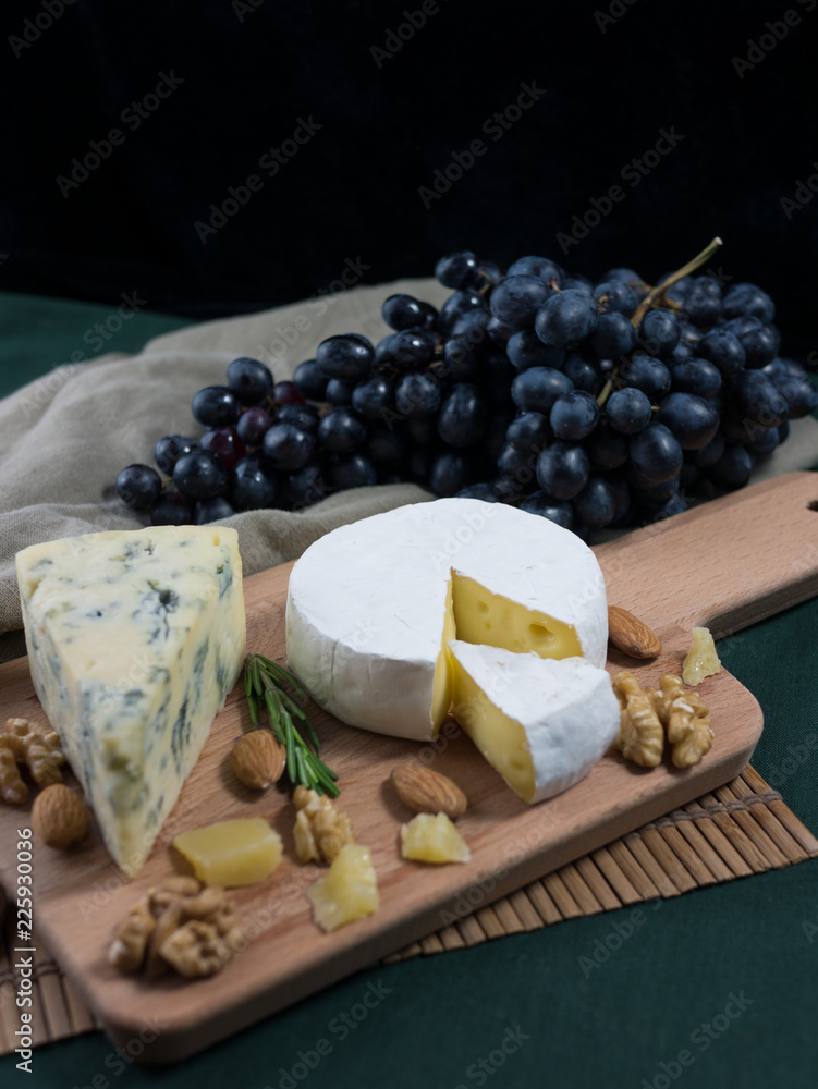 Variation of cheese, grapes and nuts on a wooden board